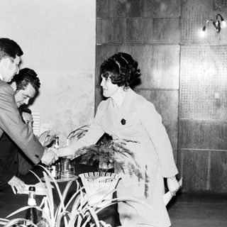 Man receives an award from a woman, onlookers applaud.