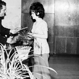 Man presenting a certificate to a woman, onlookers present.