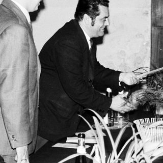 Man presenting a certificate to a woman, onlookers present.