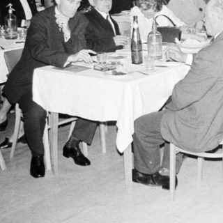 Group of formally dressed people dining at a large table.