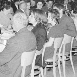 Group of formally dressed people dining at a large table.