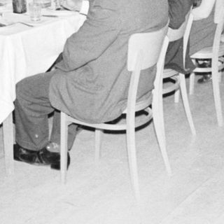 Group of formally dressed people dining at a large table.