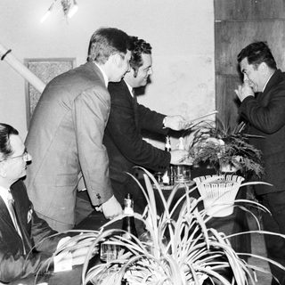 Men in suits appear to be discussing something intently.