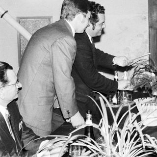 Men in suits appear to be discussing something intently.