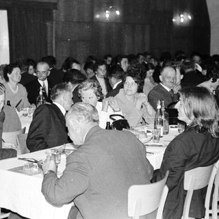 Group of formally dressed people dining at a banquet.