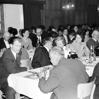 Group of formally dressed people dining at a banquet.