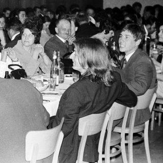 Group of formally dressed people dining at a banquet.