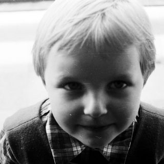 Black and white portrait of a young boy looking forward.