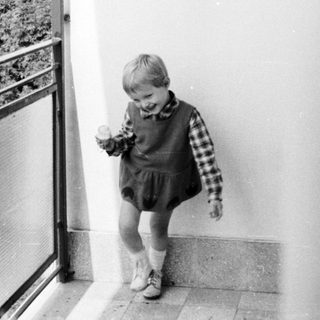 Black and white photo of a young boy on a balcony.