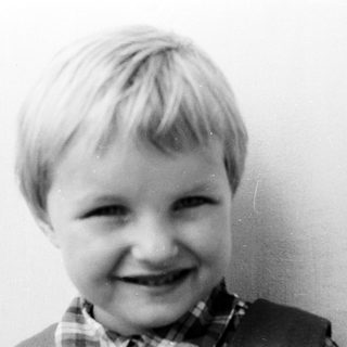 Here's a brief summary of the image: Black and white portrait of a smiling young boy.