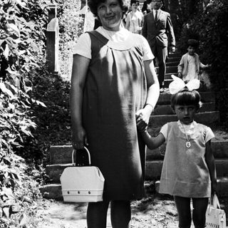 Woman and child stand on steps, people ascend in background.