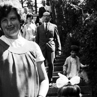 Woman and child stand on steps, people ascend in background.