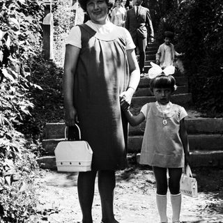 Woman and child stand on steps, people ascend in background.