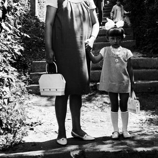 Woman and child stand on steps, people ascend in background.