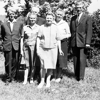 Group portrait of five people standing near a church.