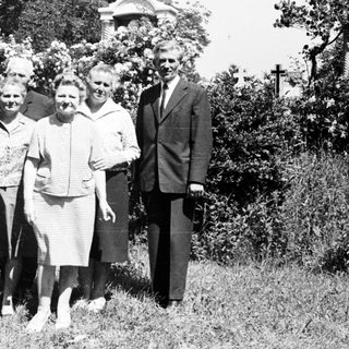 Group portrait of five people standing near a church.