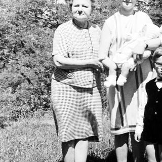 Black and white photo of four people standing in grass.