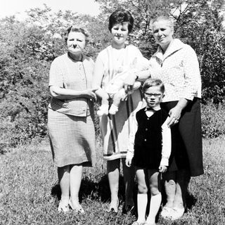 Black and white photo of four people standing in grass.