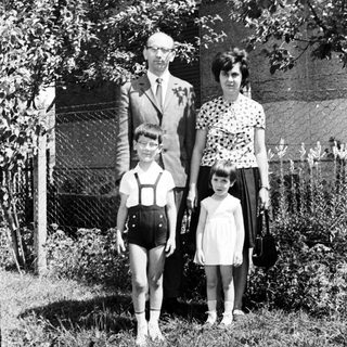 Family portrait, 1960s, standing in front of a house.