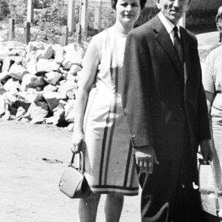 Family portrait in front of houses, carrying baskets.