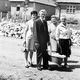 Family portrait in front of houses, carrying baskets.