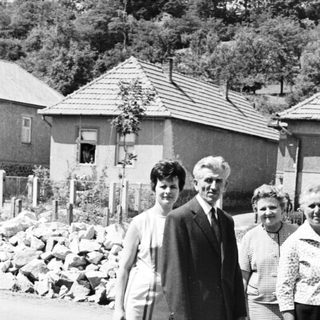 Family portrait in front of houses, carrying baskets.