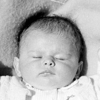 Black and white photo of a baby in a cradle.