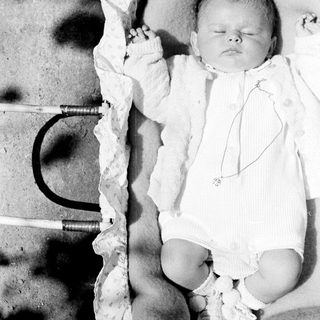 Black and white photo of a baby in a cradle.