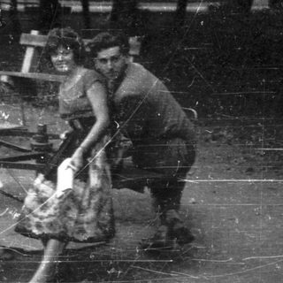 Three people sit together outdoors near a picnic table.