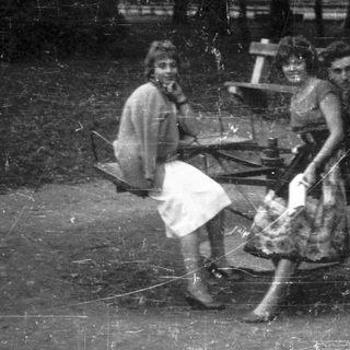 Three people sit together outdoors near a picnic table.