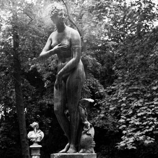 Classical statue of a woman stands on a pedestal.