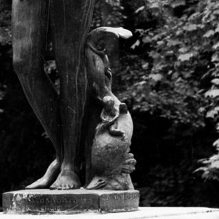 Classical statue of a woman stands on a pedestal.