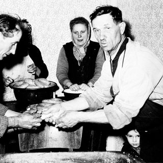Family making bread in a humble, older kitchen setting.
