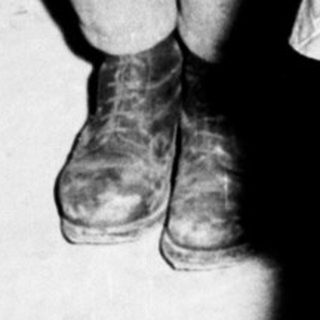 Young boy stands near medical equipment, possibly during wartime.