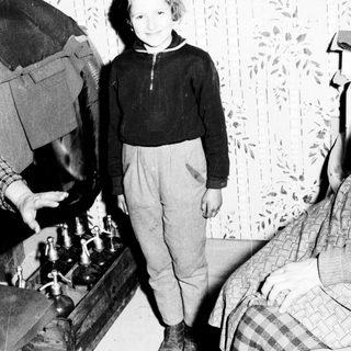 Young boy stands near medical equipment, possibly during wartime.