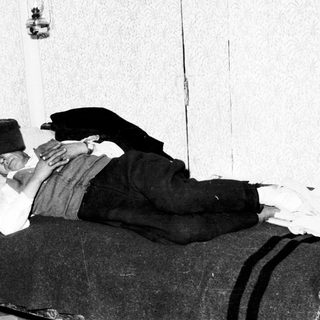 Injured man lies in bed, supported by a pillow.