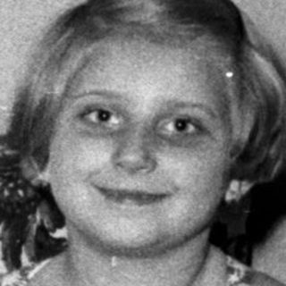 Young girl in a swimsuit sits on a floral sofa.