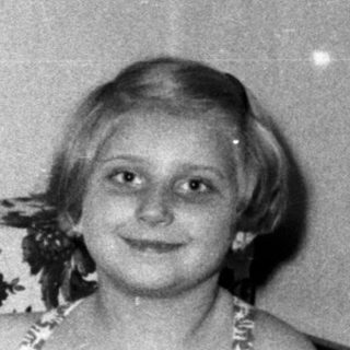 Young girl in a swimsuit sits on a floral sofa.