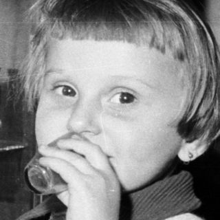 Black and white photo of a child near a cabinet.