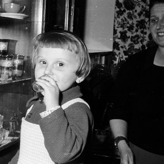 Black and white photo of a child near a cabinet.
