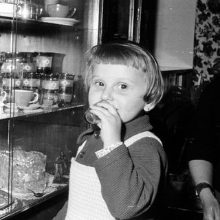 Black and white photo of a child near a cabinet.