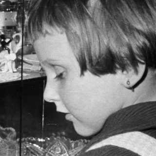 Boy gazes intently at a display case filled with delicate items.