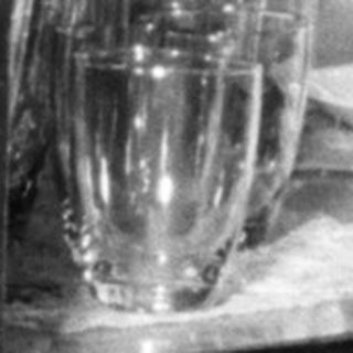 Boy reaches for a glass in a china cabinet.