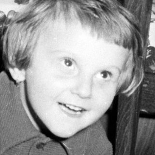 Black and white photo of a child playing under a table.