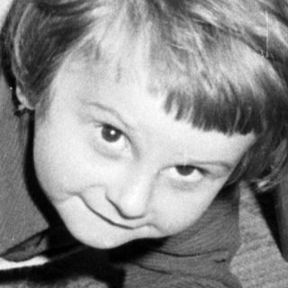 Black and white photo of a child crawling under a table.