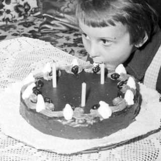 Here's a brief summary of the image: Child blows out candles on a cake.