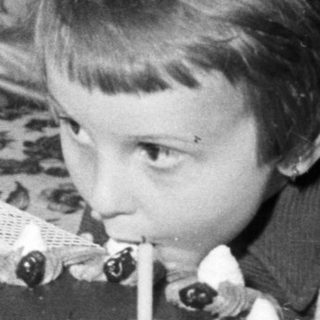 Here's a brief summary of the image: Child blows out candles on a cake.