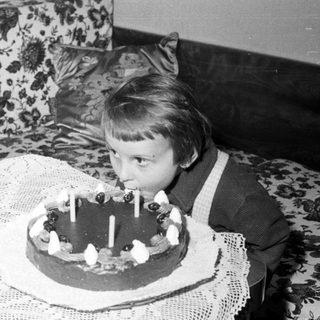 Here's a brief summary of the image: Child blows out candles on a cake.