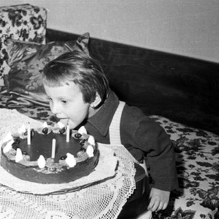 Child blows out candles on a cake indoors.