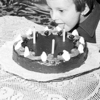 Child blows out candles on a cake indoors.
